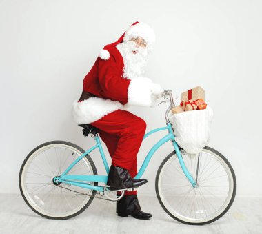 Noel Baba Noel hediyeleriyle dolu eski bir bisiklete biniyor.