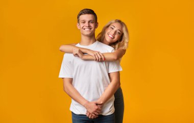 Sarı arka planda kucaklaşan genç romantik çift
