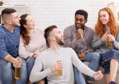 Evde karaoke partisi. Mutlu arkadaşlar şarkı söyleyip bira içiyorlar.