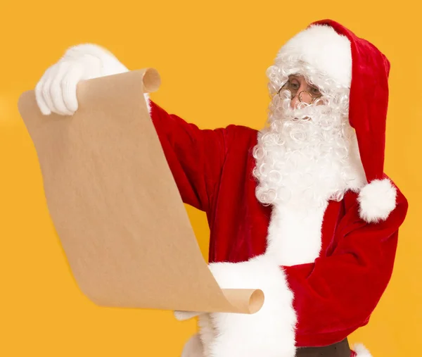 Papá Noel chequeando la lista de deseos de los niños en papel — Foto de Stock