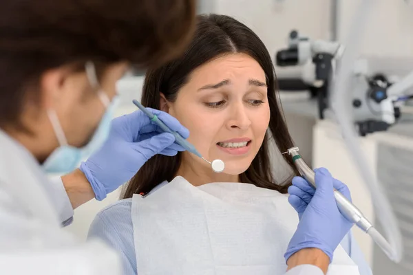 Mulher assustada no consultório odontológico, olhando em pânico para ferramentas dentárias — Fotografia de Stock