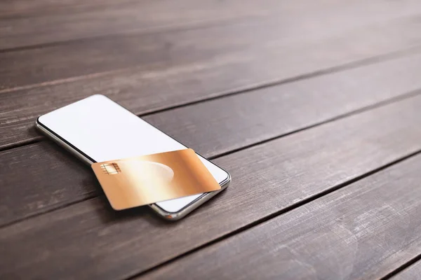Smartphone s prázdnou obrazovkou a kreditní kartou na dřevěném stole — Stock fotografie