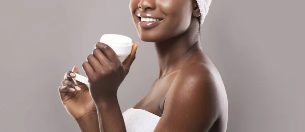 Mujer negra sosteniendo frasco abierto de crema facial en las manos — Foto de Stock