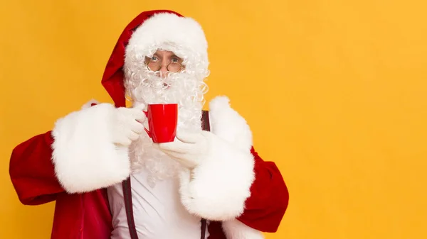 Feliz Santa segurando bebida quente em copo vermelho em laranja — Fotografia de Stock