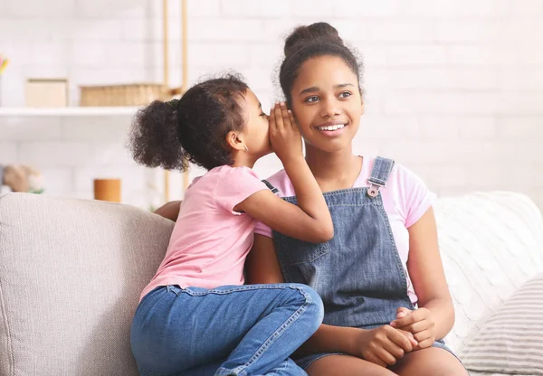 Linda niña africana susurrando algo a su hermana mayor oreja — Foto de Stock