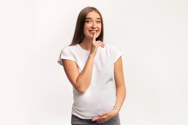 Femme enceinte Gesturing Hush signe debout sur fond de studio blanc — Photo