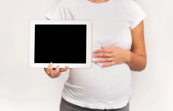 Mulher grávida irreconhecível mostrando tela do comprimido no estúdio, corte, Mockup — Fotografia de Stock