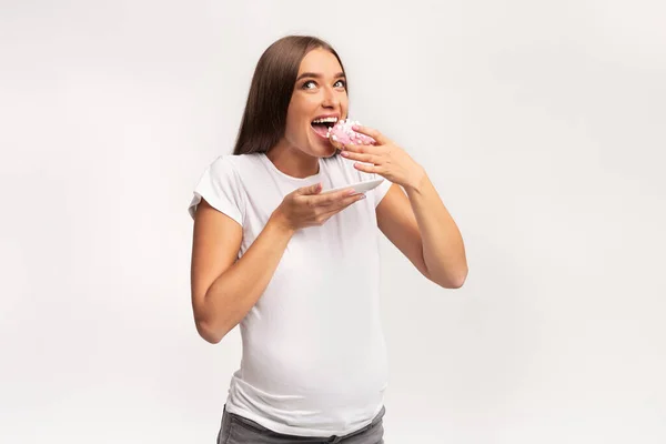 Excited Pregnant Lady Eating Donut Standing Over White Studio Background — Stock Photo, Image