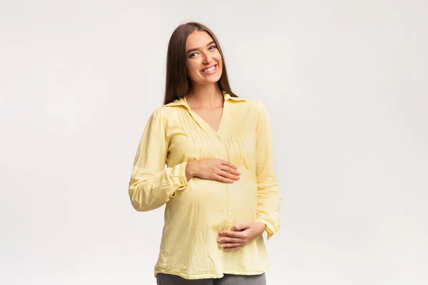 Smiling Pregnant Woman Touching Belly Standing Over White Background — Stock Photo, Image