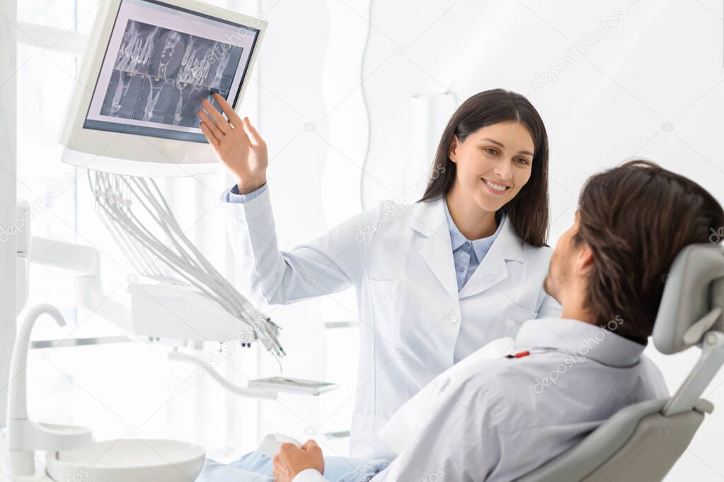 Beautiful female dentist doctor showing her patient x-ray results