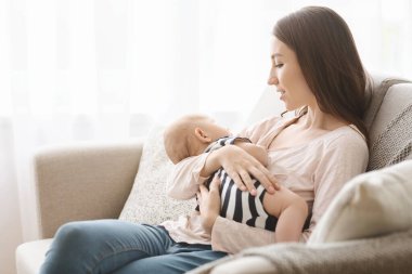 Büyüleyici yeni doğmuş bebek emzirdikten sonra annesinin kollarında uyuyakaldı.