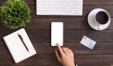 Unrecognizable office employee using smartphone with blank screen at workplace.