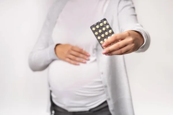 Irriconoscibile signora incinta che mostra pillole in posa su sfondo bianco, Ritagliato — Foto Stock