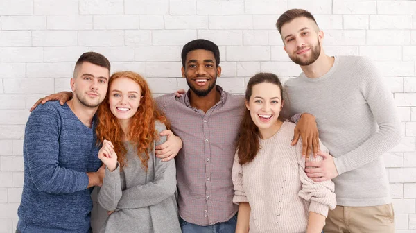 Groupe d'amis heureux embrasser et sourire à la caméra — Photo