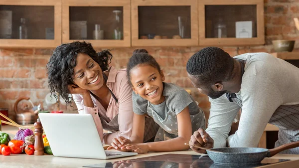 Amical afro famille en utilisant un ordinateur portable à la cuisine, à la recherche de la recette — Photo