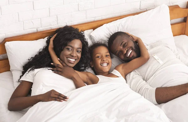 Genitori afro-americani e la loro figlia rilassarsi insieme a letto — Foto Stock