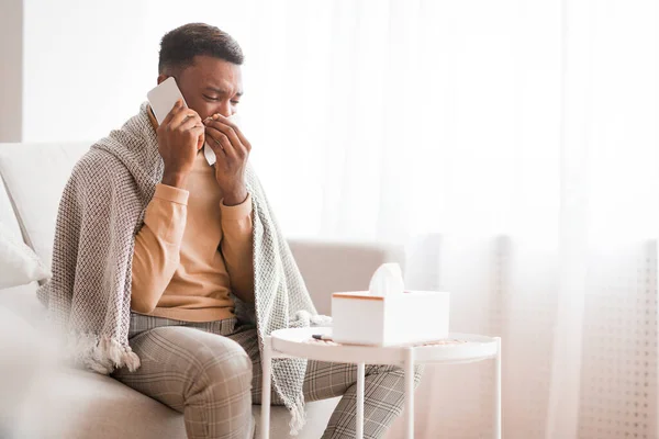 Uomo chiamando medico soffiando naso in carta tessuto a casa — Foto Stock