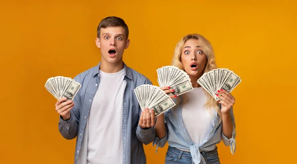 Σοκαρισμένο νεαρό ζευγάρι που κρατάει πολλά λεφτά στα χέρια του. — Φωτογραφία Αρχείου