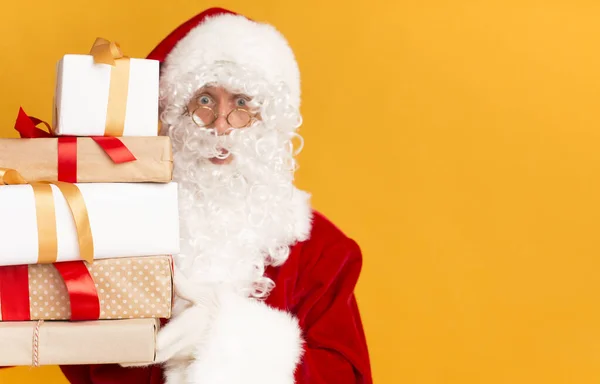 Noel Baba parlak turuncu arka planda hediye kutuları tutuyor. — Stok fotoğraf