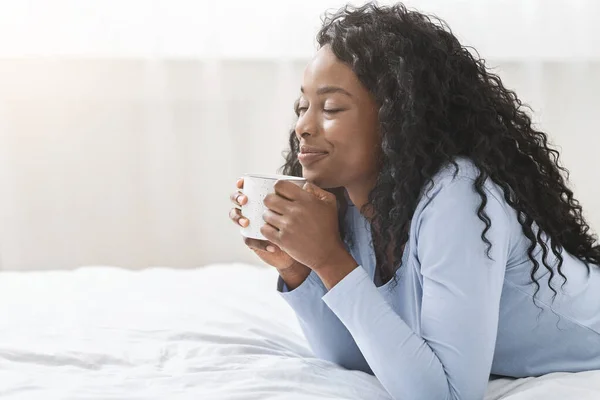 Fröhliches Mädchen entspannt sich im Bett mit einer Tasse Kaffee — Stockfoto