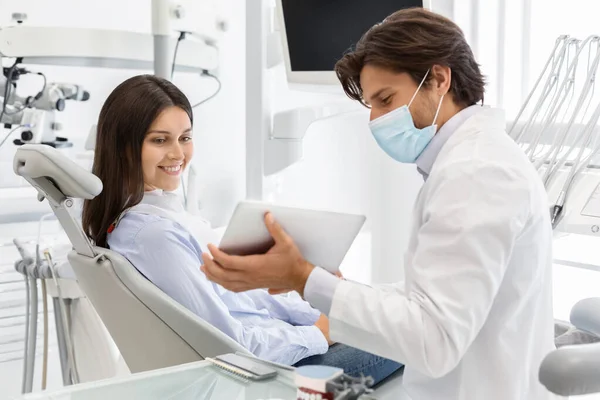 Médico dentista mostrando o resultado do tratamento do paciente em comprimido digital — Fotografia de Stock