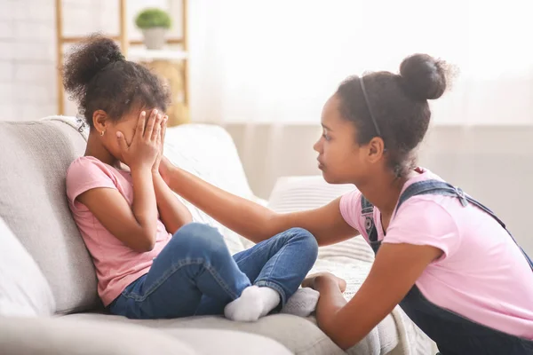Fürsorgliches afrikanisches Teenie-Mädchen beruhigt ihre traurig weinende kleine Schwester — Stockfoto