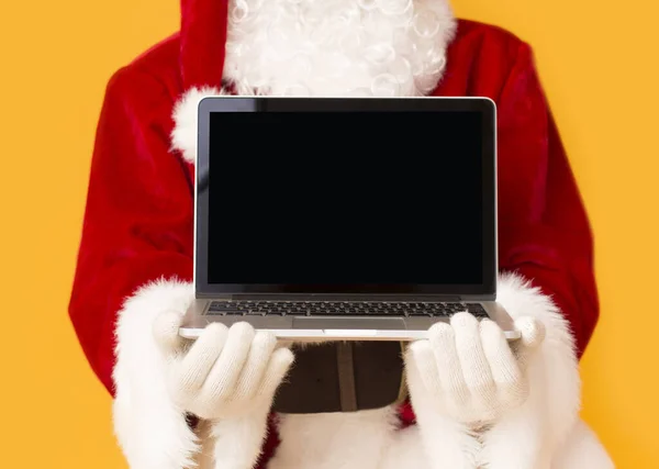 Papai Noel segurando laptop aberto com tela em branco preto — Fotografia de Stock
