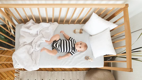 Цікава новонароджена дитина лежить у дитячому ліжечку і дивиться на камеру — стокове фото