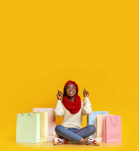Erstaunt schwarzes Mädchen mit Einkäufen, die auf leeren Raum zeigen — Stockfoto