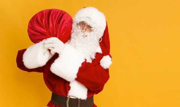 Weihnachtsmann quält sich mit Geschenken aus großem roten Sack — Stockfoto