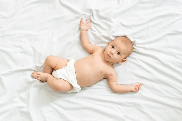 Portret ciekawskiego noworodka w pieluszce leżącego na łóżku — Zdjęcie stockowe