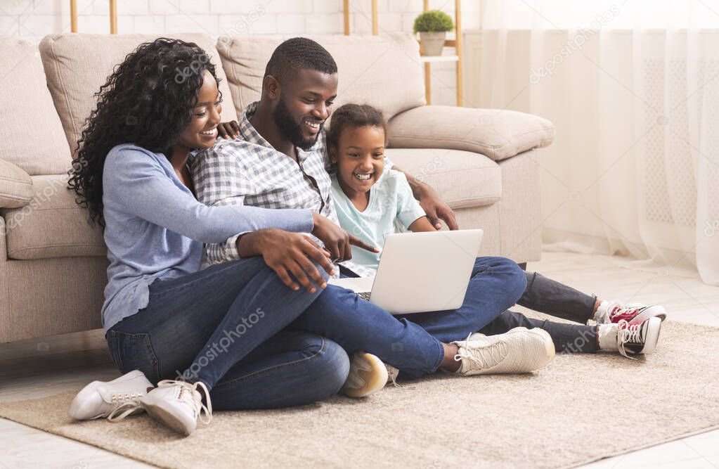 Black family of three using laptop together at home