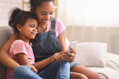 Afrikalı genç kız küçük kız kardeşine cep telefonu kullanmayı öğretiyor.
