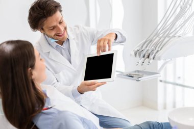 Boş dijital tablet ekranı gösteren yakışıklı dişçi