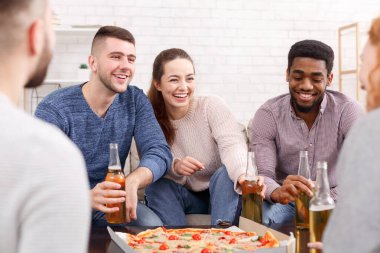 Heyecanlı arkadaşlar evde pizza yiyip konuşuyorlar.