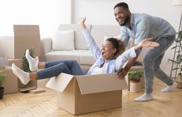 在新房子里，兴奋的男人骑着女人在移动的箱子里 — 图库照片