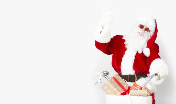 Feliz Santa en gafas de sol montando una bicicleta con regalos a países cálidos — Foto de Stock