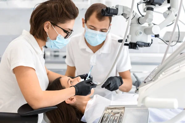 Dentistas altamente qualificados fazendo tratamento na clínica odontológica moderna — Fotografia de Stock