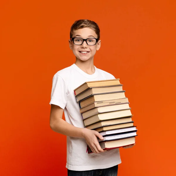 Mądry nastolatek w okularach trzymający stos książek — Zdjęcie stockowe
