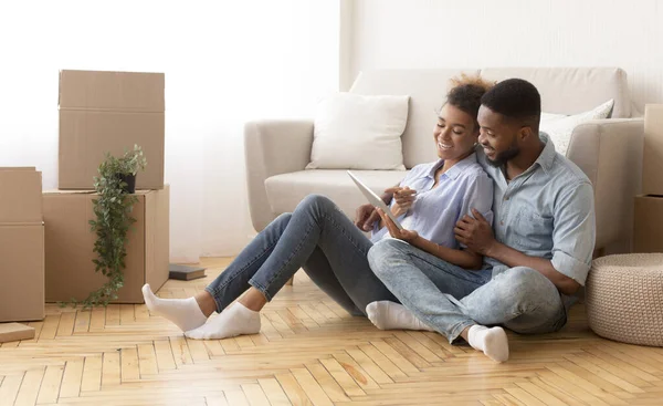 Spouses Using Tablet Sitting On Floor Among Unpacked Boxes Indoor — Stockfoto