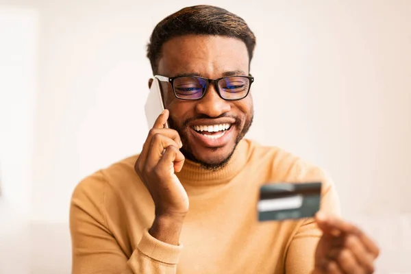 Man Holding Credit Card Consulting On Phone At Home — Stock Photo, Image