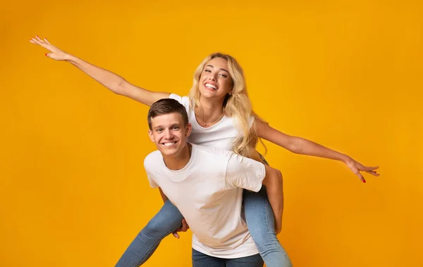 Alegre millennial casal se divertindo juntos sobre amarelo fundo — Fotografia de Stock