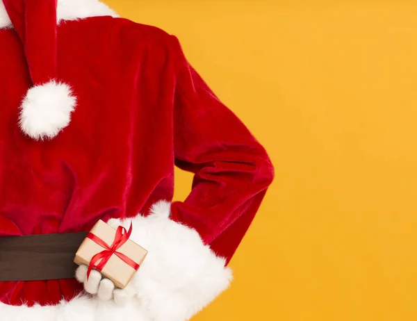 Listige Weihnachtsmann versteckt Geschenk in der Hand auf orangefarbenem Hintergrund — Stockfoto