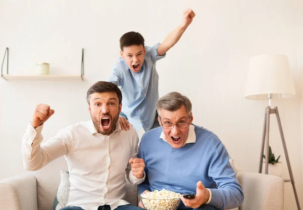 Abuelo, padre e hijo viendo el partido de fútbol en la televisión interior — Foto de Stock