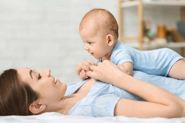 Cute newborn baby relaxing on bed with mom — Stock Photo, Image