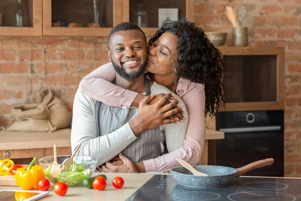 Retrato de una encantadora pareja negra abrazándose en la cocina — Foto de Stock