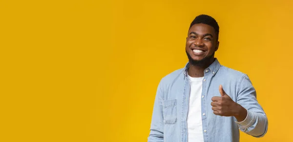 Happy african guy gesturing thumb up on yellow background — 스톡 사진