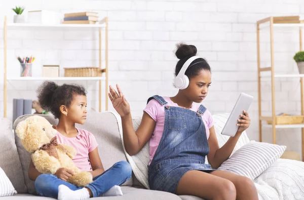 Africano adolescente menina ignorando sua irmãzinha, assistindo filme no tablet digital — Fotografia de Stock