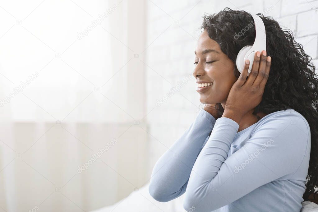 Side view of afro girl with closed eyes listening music