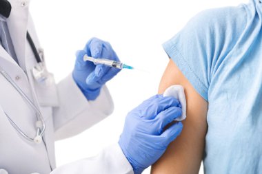 Doktor aşı yapıyor, mavi eldiven ve tıbbi önlük giyiyor.
